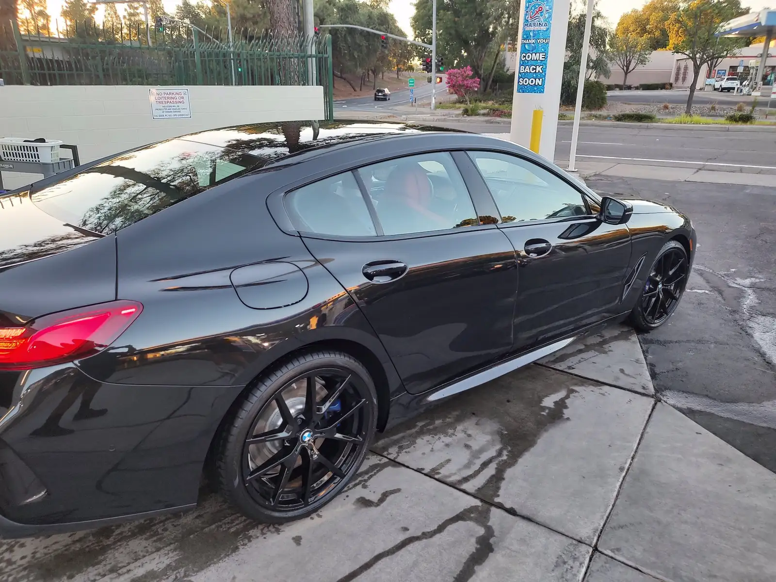 Black BMW coupe parked on the wet Marina Express lot after a wash